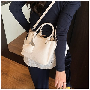 Detail of cream bucket bag with pebble texture, heart charm and fashion logo print