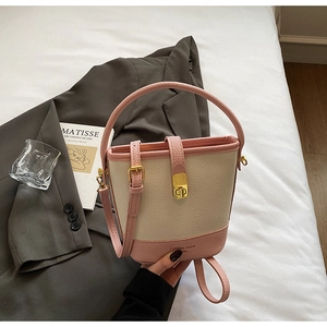 Détail du sac seau bicolore rose et beige avec texture grainée et boucle dorée