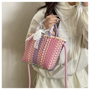 Detail of woven crossbody bag with pink lace bow and colorful checkered pattern