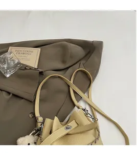 Detailed view of beige lychee leather bucket bag with silver hardware and bear charm