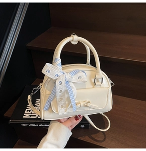 Detail of cream white Boston bag with blue checkered lace ribbon and bow front pocket
