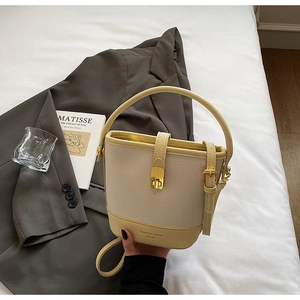 Détail du sac seau beige montrant le grain de litchi et le fermoir doré métallique