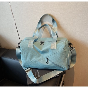 Close-up of light blue nylon gym bag showing front zipper pocket and webbing handles