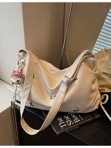 Chic pleated cream dumpling bag with metallic butterfly detail and plush charm accessory