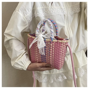 Detail of woven pastel basket bag with delicate lace bow and pink crossbody strap