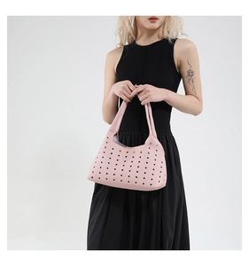 Detailed macro of pink lychee leather handbag featuring decorative metal grommets pattern