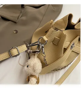 Detail of cream lychee leather bucket bag with silver hardware and a cute sheep pendant