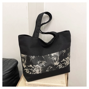 Détail du sac cabas en toile noire avec imprimé bambou sur un support de livre