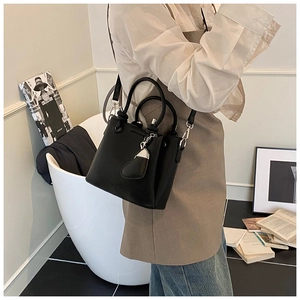 Detail of black lychee grain bucket bag with dual handles and metal leather charm