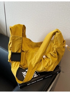 Bright yellow nylon dumpling crossbody bag with adjustable black buckle strap and drawstring