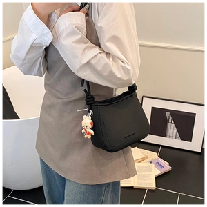 Detail view of black lychee grain crossbody bucket bag with cartoon rabbit charm