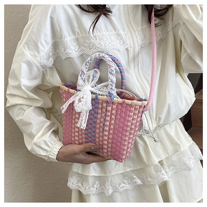 Close-up of pink and blue woven handbag with lace bow detail and shoulder strap