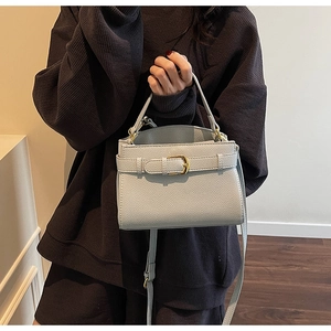 Détail du sac à main en cuir grainé gris clair avec boucle dorée et poignée chic