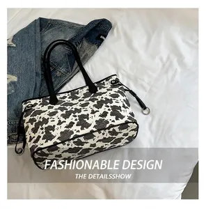 Dettaglio della borsa tote con stampa mucca, tablet e giacca di jeans su stoffa