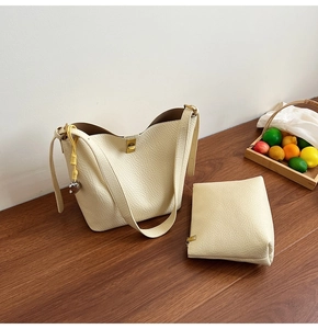 Detail of cream white leather bucket bag with matching pouch and silver heart charm pendant