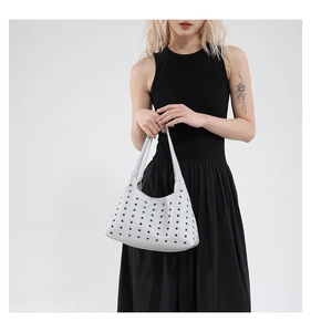 Detailed close-up of metallic silver grommets and rivet texture on the underarm bag