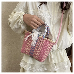 Close-up of woven handbag with pink and blue patterns and a white lace bow detail