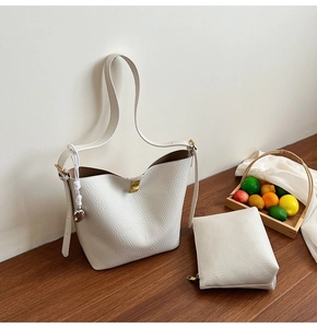 Detail view of cream white bucket bag set with litchi grain leather and gold metal twist lock