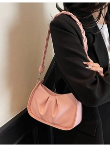 Pink pleated dumpling shoulder bag with woven strap shown on model in a minimalist setting