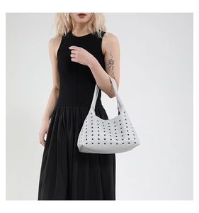 Detailed view of silver hobo bag with metal eyelets worn over the shoulder by a model