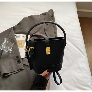 Gros plan détaillé d'un sac seau en cuir grainé noir avec un élégant fermoir doré