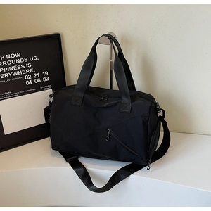 Detail of black nylon travel bag featuring reinforced handles and adjustable shoulder strap