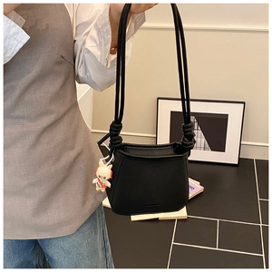 Detail of black lychee-grain leather bucket bag with a cute rabbit doll charm