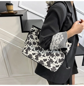 Dettaglio della borsa tote con stampa mucca e finiture in pelle nera su una modella