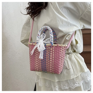 Pink and cream woven crossbody bag with lace bow detail shown on a white dress model