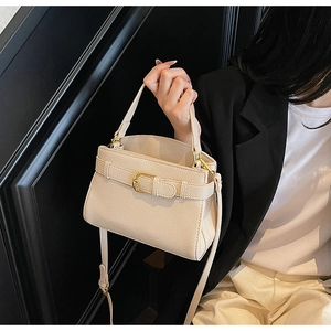 Détail de la texture cuir grainé crème et ferrures dorées sur le sac à main chic
