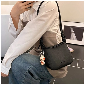 Detail of black pebble leather shoulder bag with knotted strap and bunny charm