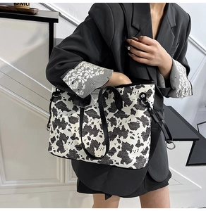 Dettaglio della borsa tote con stampa mucca, finiture in pelle nera e doppi manici