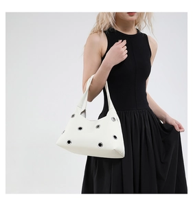 Detail of white lychee leather shoulder bag with silver grommets and broad strap
