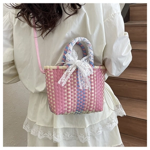 Detail of pink woven crossbody bag with white lace bow on white dress background