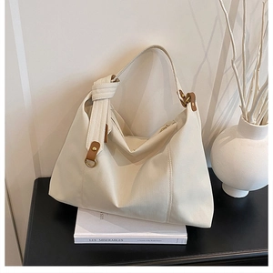 Close-up of pleated beige tote bag with brown leather accents and metal D-ring details