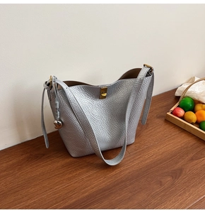 Detail of silver lychee grain leather bucket bag with gold lock and heart charm