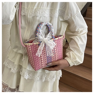 Detail of hand-woven pink mini bag featuring a large white lace bow on the handle
