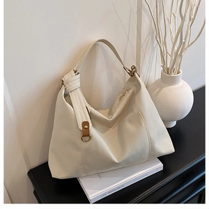 Detail of cream white oversized tote bag with gold hardware on black background