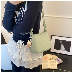 Sage green bucket bag featuring a knotted shoulder strap and a cute bunny pendant charm