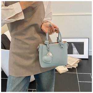 Close-up of light blue lychee pattern leather handbag with heart charm and zipper