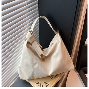 Detail view of large cream tote bag with brown leather handles and back zipper pocket