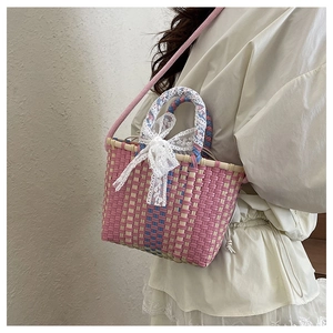 Detail of woven crossbody bag featuring pink lace bow and delicate lace handle