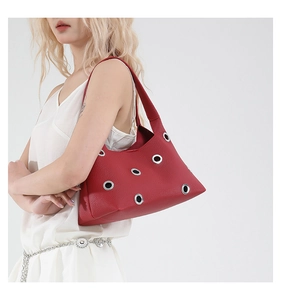 Detail of red pebbled leather shoulder bag with industrial silver grommet accents