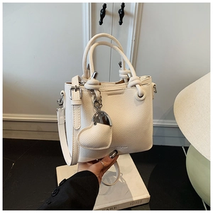Macro detail of white lychee leather bucket bag with silver hardware and heart charm
