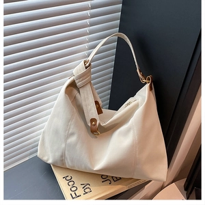 Close-up of cream canvas tote bag featuring knot detail and metallic hardware accents