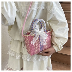 Detail of hand-woven basket bag with pink lace bow decoration on a shoulder strap