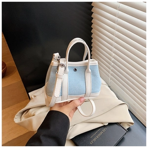 Detail of mini light blue denim crossbody bag with white leather trim and metal buckle