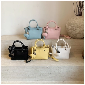 Litchi pattern bucket bags in five colors with heart charms on stone steps