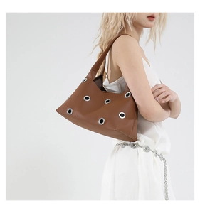 Detail of brown leather underarm bag with silver eyelet accents and pebbled texture