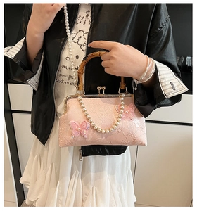 Detail of pink floral jacquard bag featuring bamboo handle and tulle butterfly accents